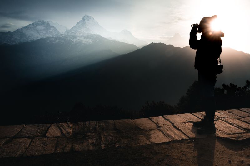 Man drinking tea standing with view of annapurna mountains at sunrise