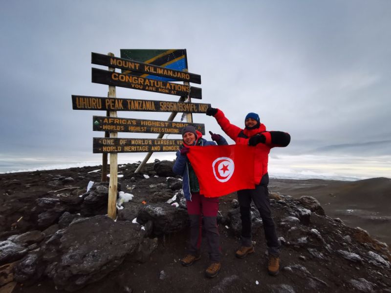 Arwa and Matthieu at Uhuru Peak with Tunisian flag on Kilimanjaro