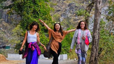 three happy women friends walking on road