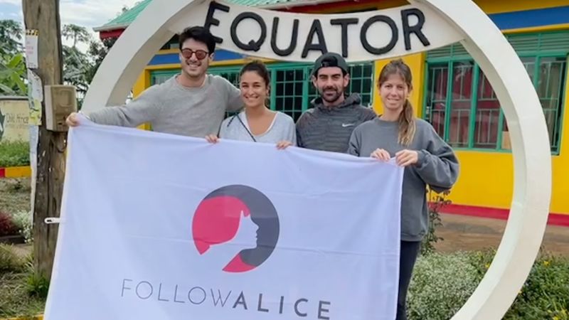 Follow Alice flag and group at Uganda Equator sign