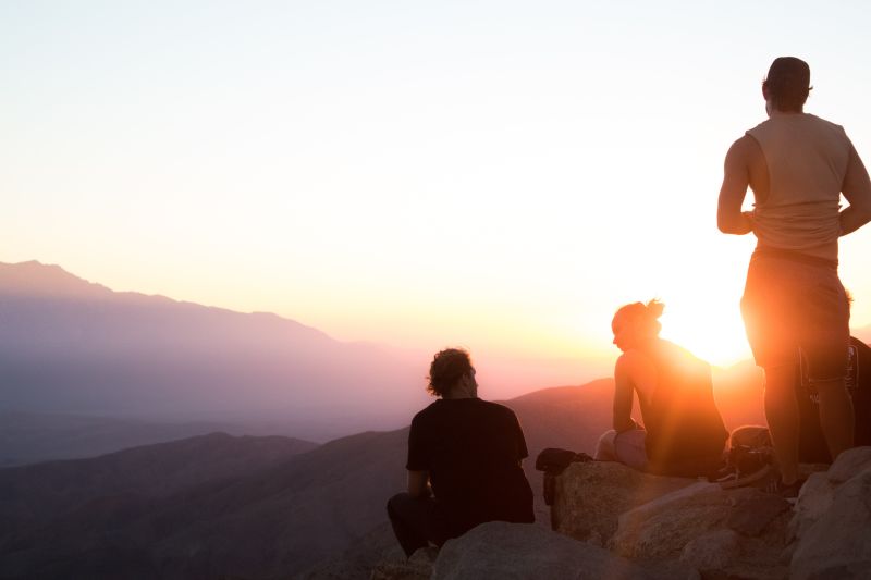 silhouette of three adults on hike in mountains