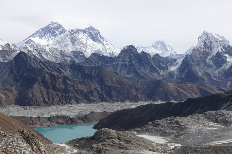 Gokyo Lake and a small settlement on its shore, surrounded by towering Himalayan peaks toped with snow