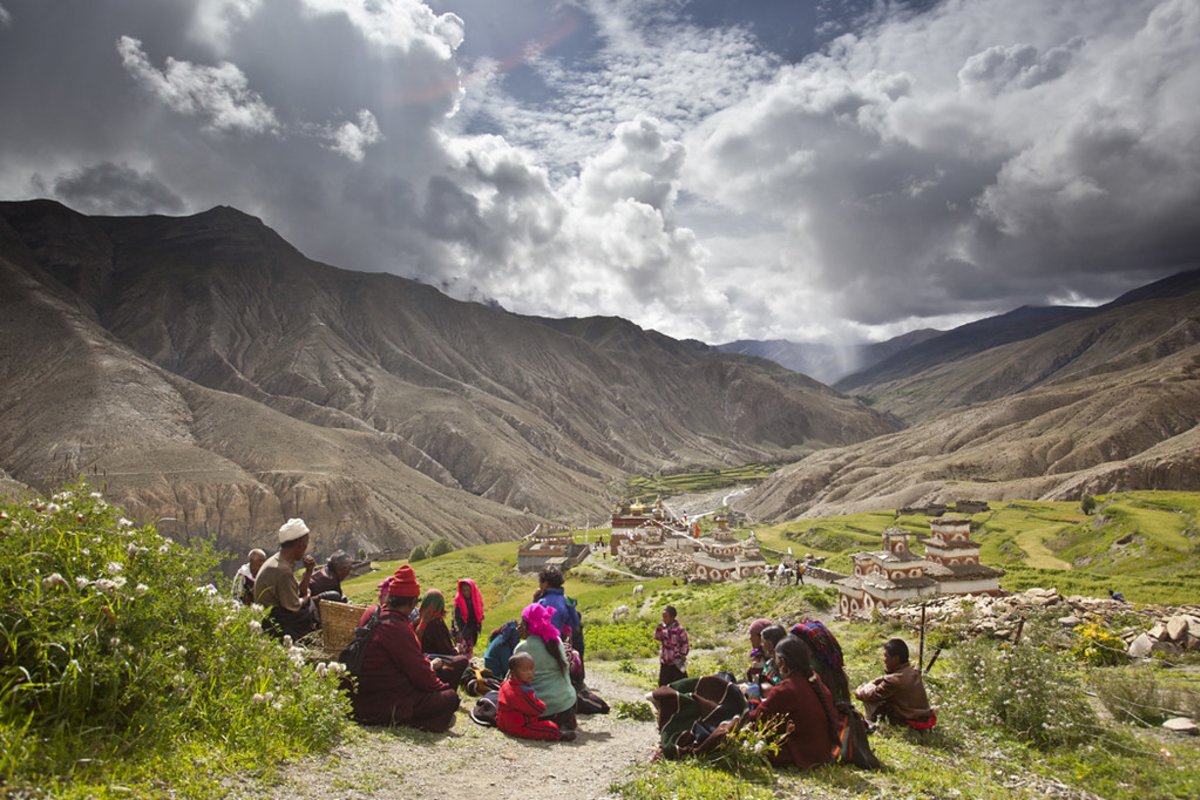 Locals sit on the grass with Saldang Gompa behind them | Image by Samir Jung Thapa