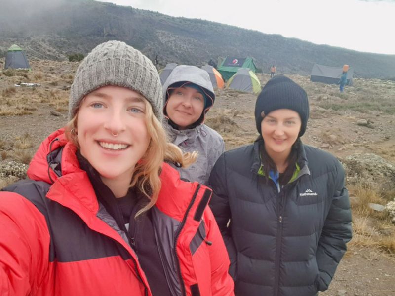 Three smiling women at a campsite on Kilimanjaro