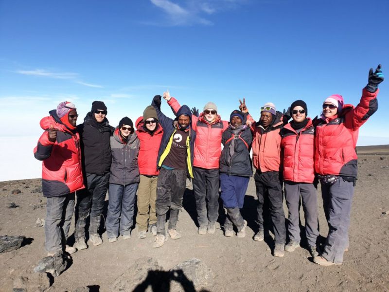 Hikers celebrating at the summit of Kilimanjaro with a group photo