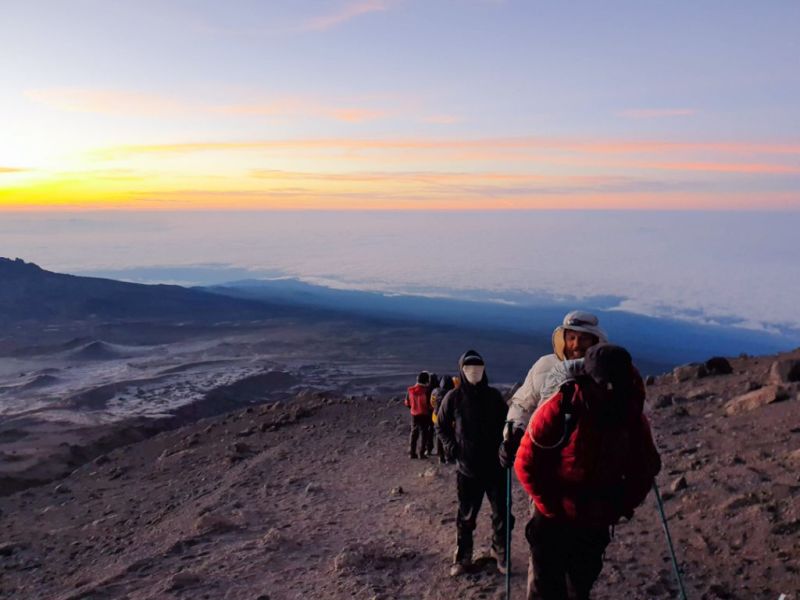 Trekkers hiking above the clouds on Mt Kilimanjaro as the sun rises