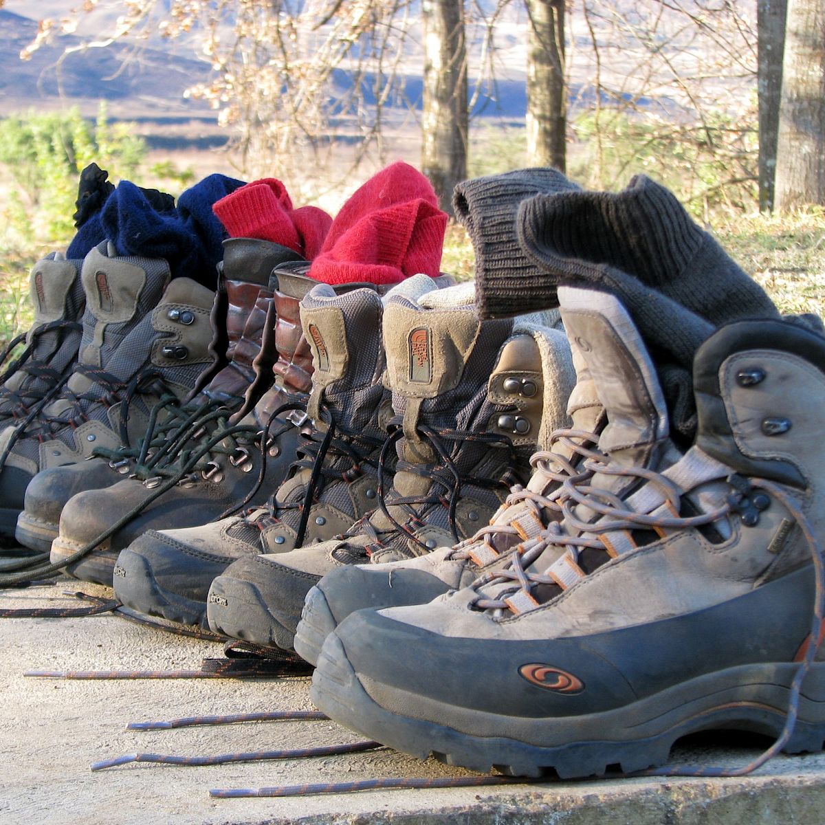 Four pairs of hiking boots and socks lined up alongside each other