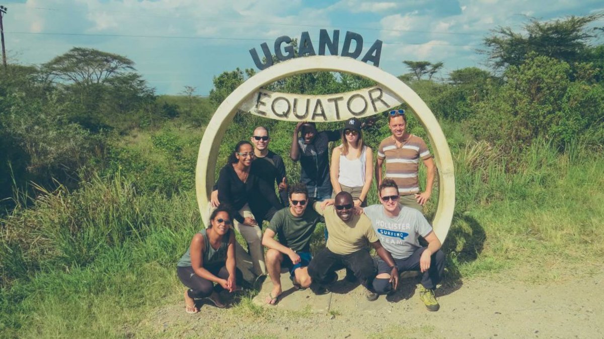 Group of travellers standing by the Uganda Equator sign
