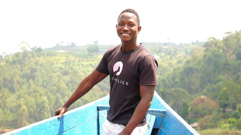 Smiling man with green Ugandan landscape in background