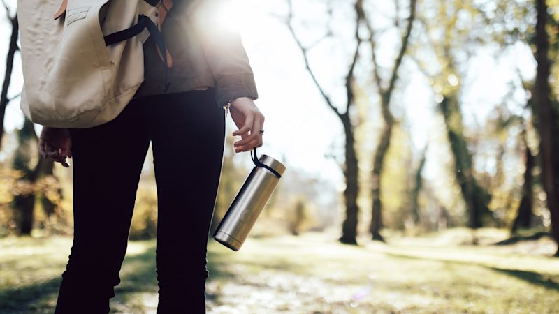Woman's hand holding a water bottle in the woods