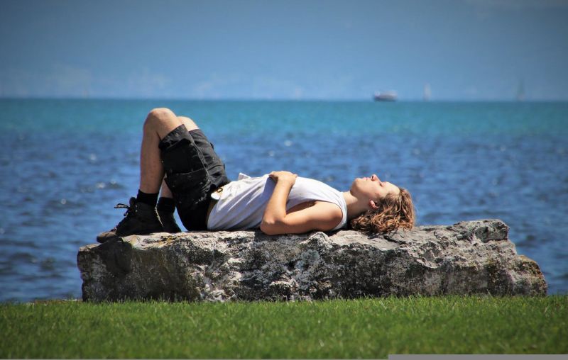 Young man lying on a rock in the sun by the sea