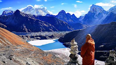 Buddhist monk in traditional red robe standing in Himalayas along Everest Base Camp trek route