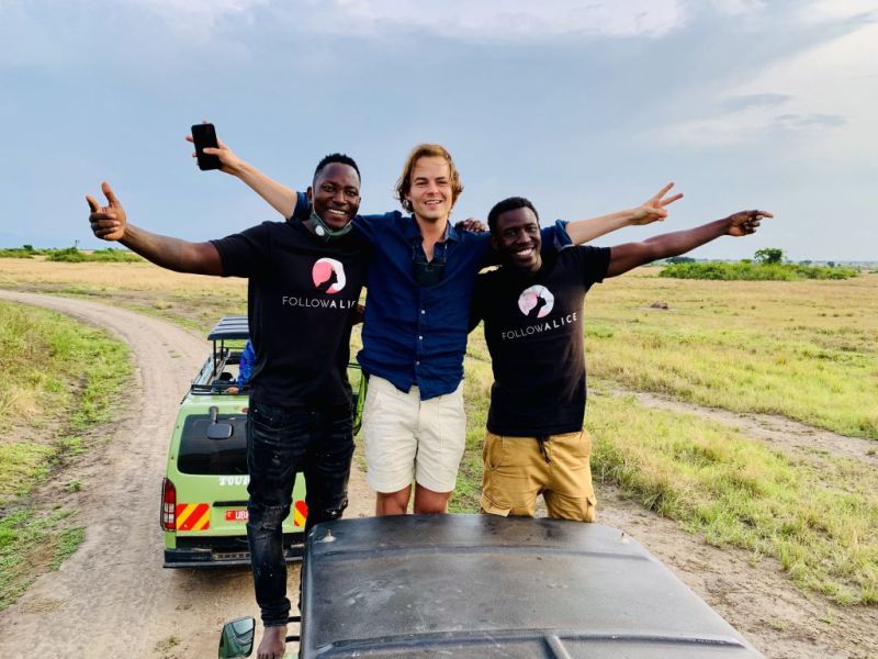 Men smiling while standing on a safari vehicle in a Uganda game park