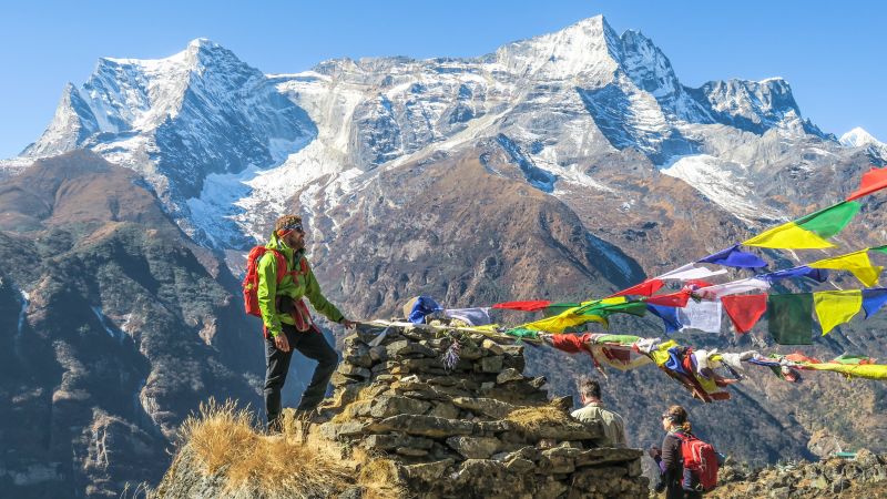 A trekker stands by Tibetan prayer flags near to Namche Bazaar, a town that sits along the Everest Base Camp trail and is a common acclimatisation rest stop