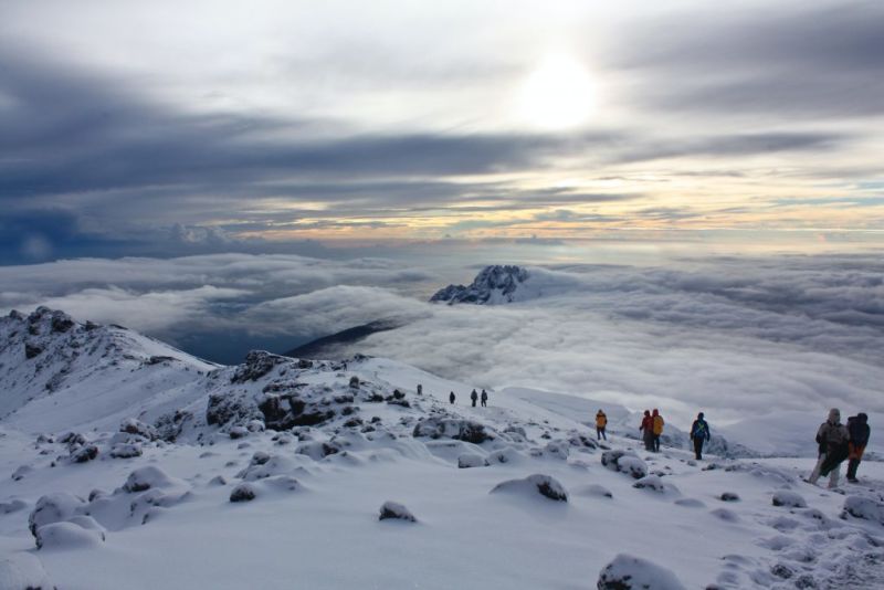 Trekkers walking through snow near summit of Mount Kilimanjaro