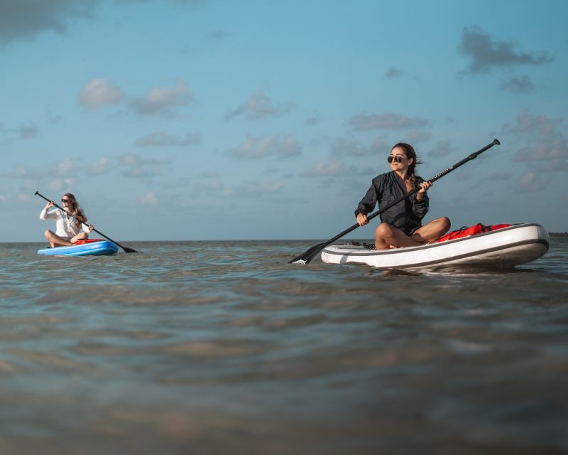 Two women paddle boards ocean
