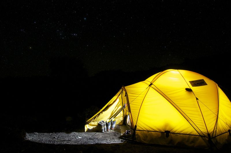 yellow tent lit up from inside under dark night sky