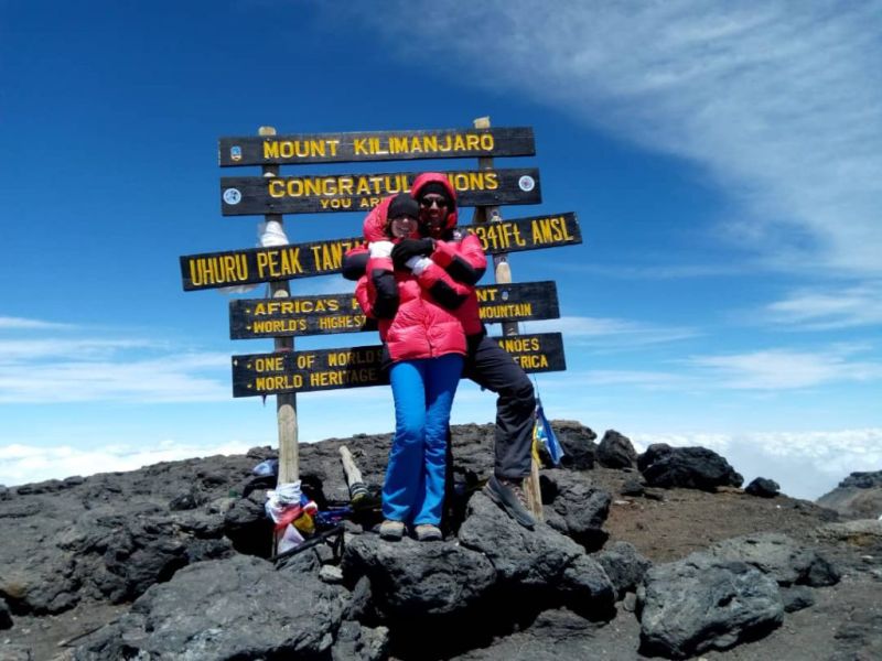 Smiling man and woman at summit of Kilimanjaro