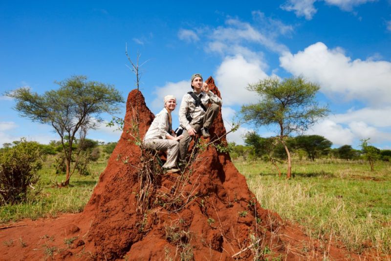Large red termite mound with man and woman on it