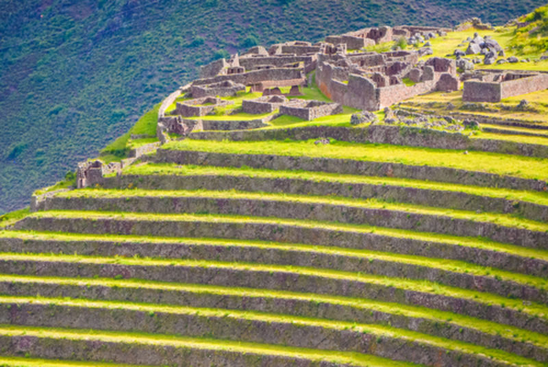 Ruins of inca town of Pisac in Peru on a green hill with farming terraces with shallow depth of field