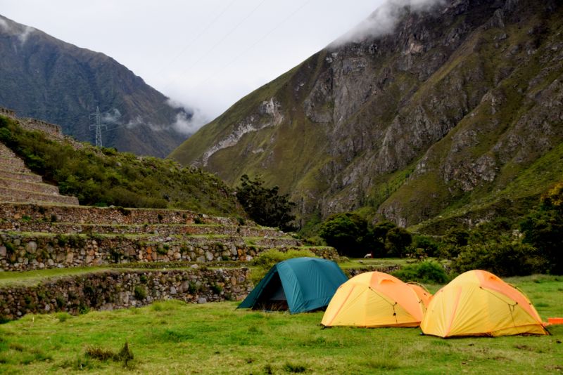 Camping in the mountains on cloudy day with tents next to old ruins on the Inca trail to Machu Picchu in Peru