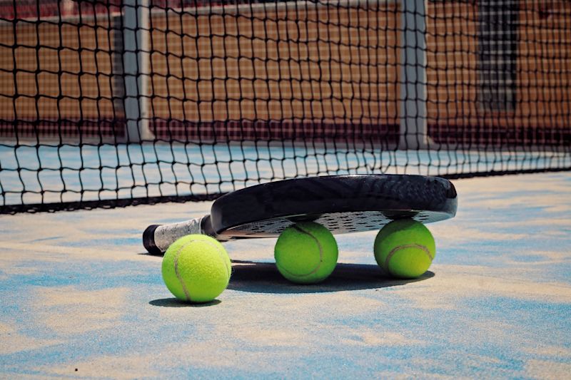 padel bat and balls on padel court floor