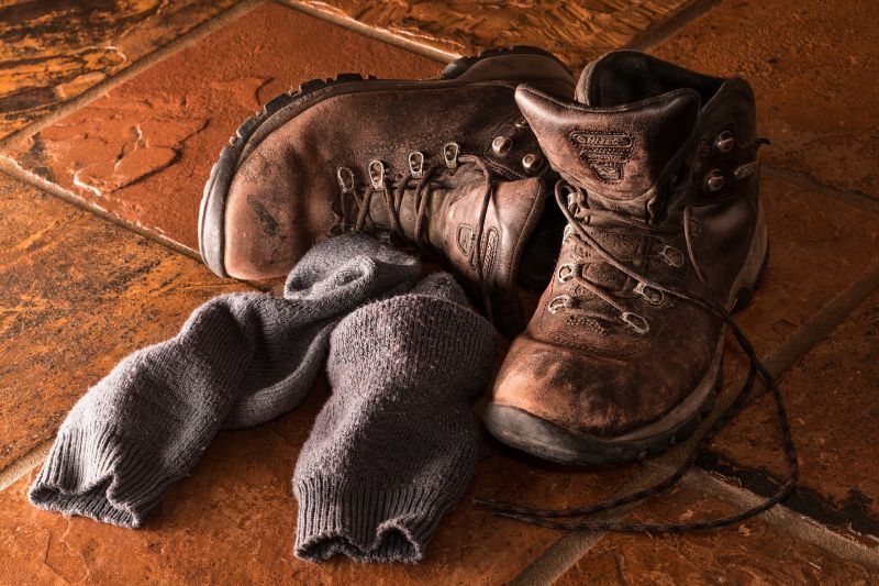 Old brown hiking boots and socks on a tiled floor