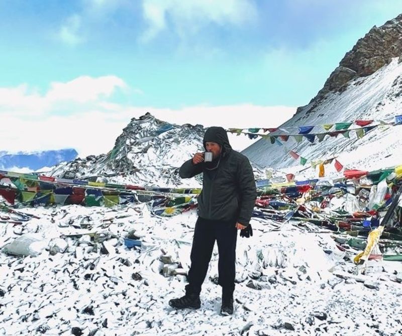 Trekker drinking hot drink at Thorung La on Annapurna Circuit