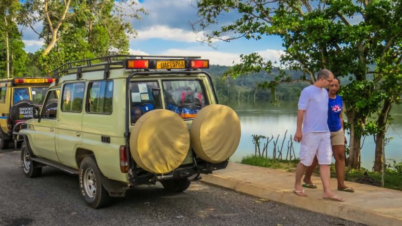 Safari vehicle and two people by body of water, safari safety tips