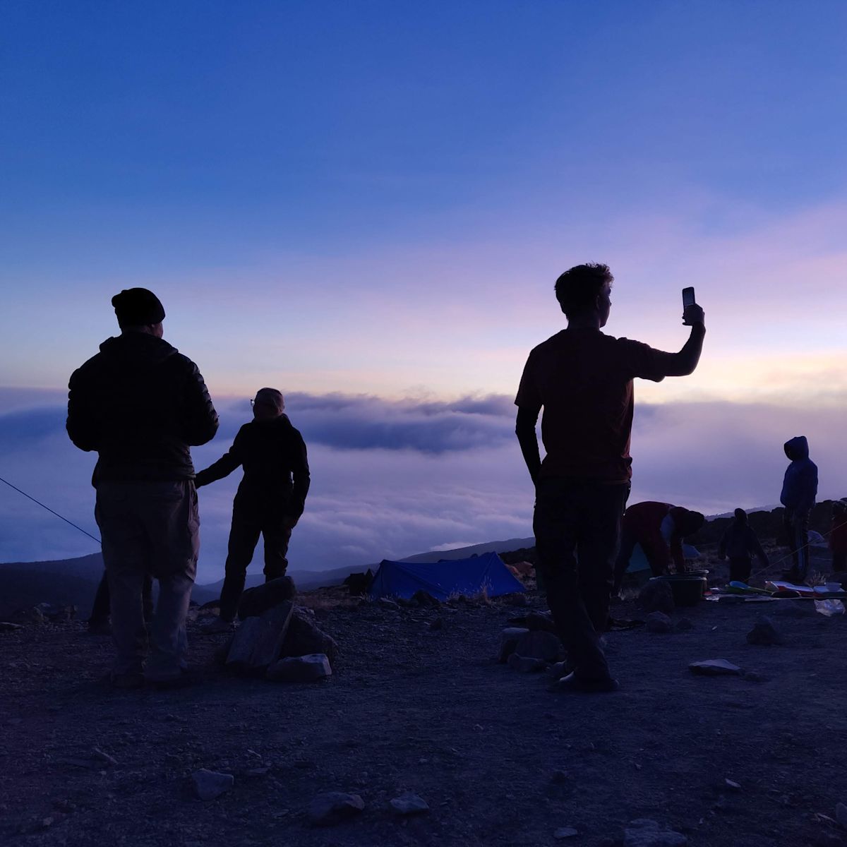 Man holds up cellphone at twilight in Karanga Camp on Kilimanjaro