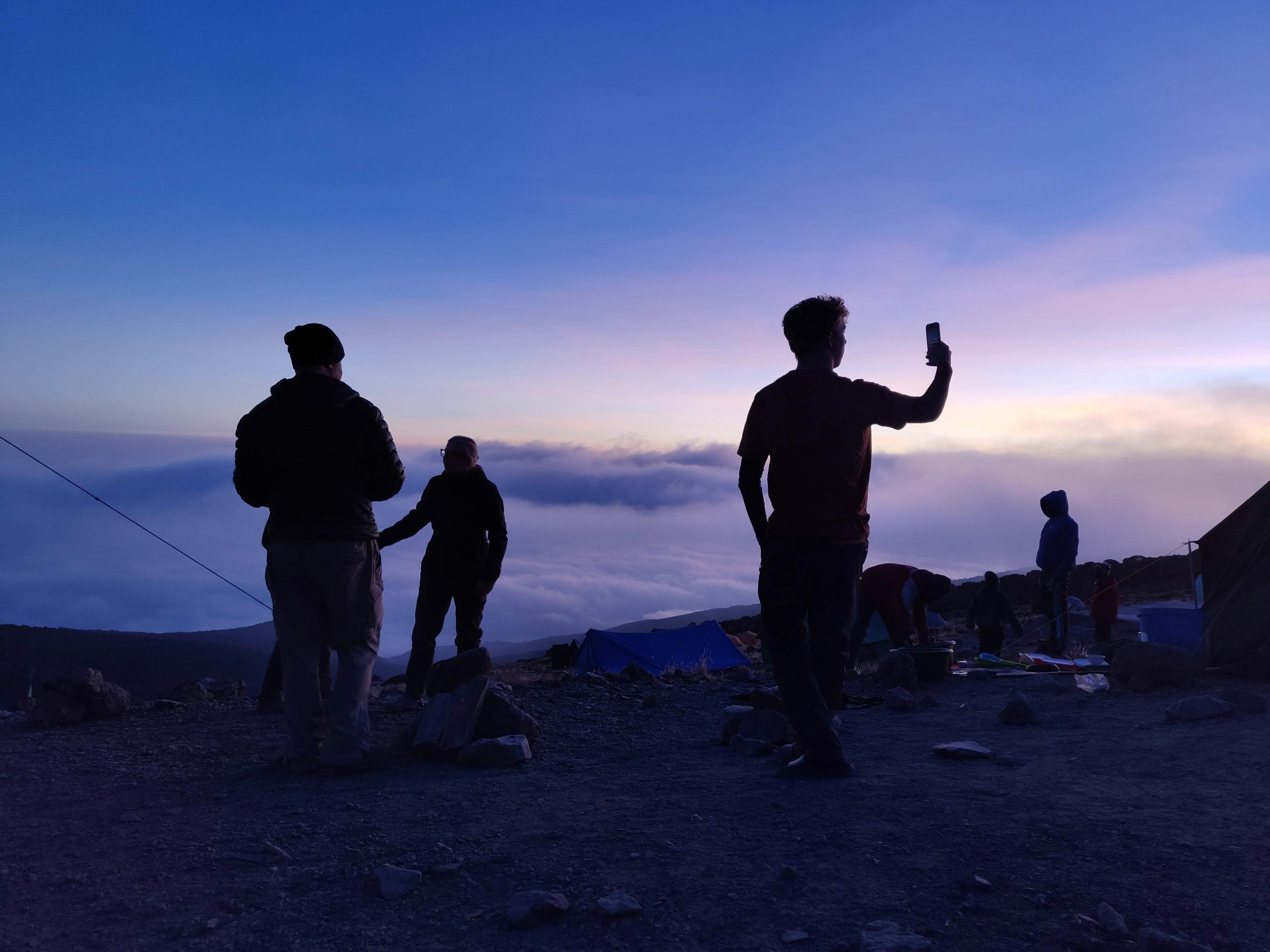 Man holds up cellphone at twilight in Karanga Camp on Kilimanjaro