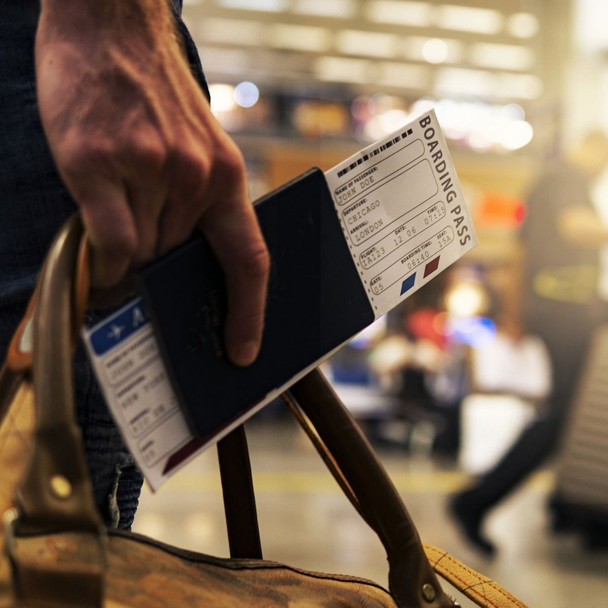 Man's hand holding a passport and boarding ticket in an airport