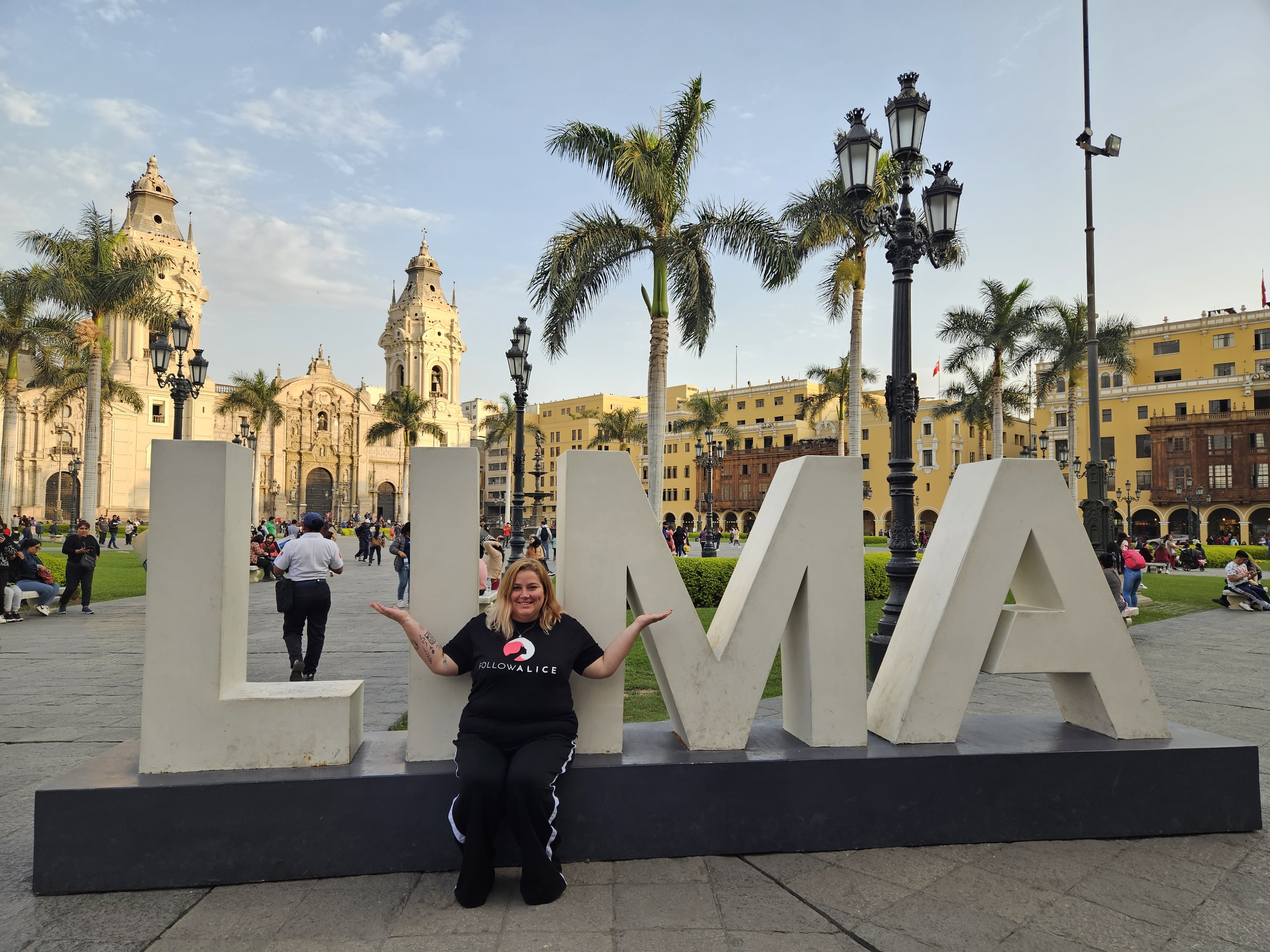 Woman seated by Lima sign, Peru