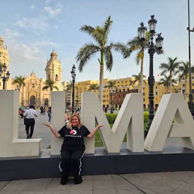 Lexy seated by Lima sign, Peru