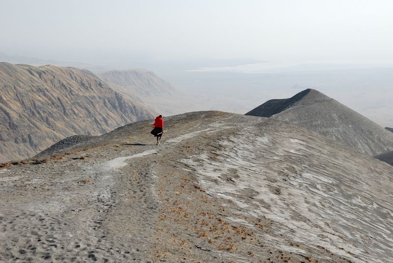 ash-covered escarpment Great Rift Valley, Maasai man in red robe