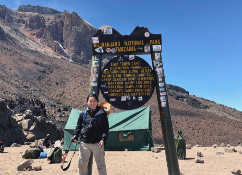 Female hiker standing beside Lava Tower sign on Kilimanjaro, August 2022