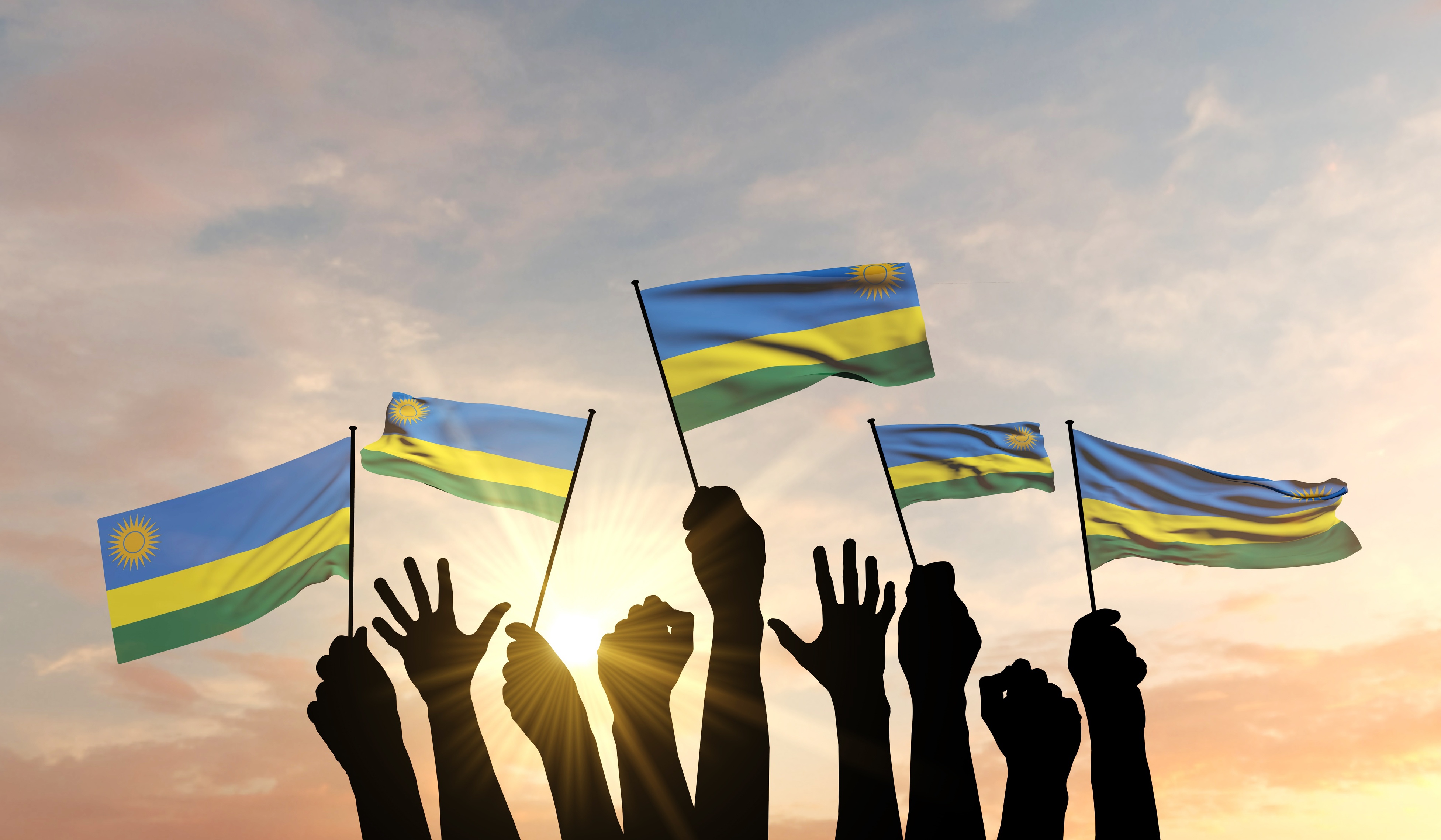 Silhouette of arms raised waving a Rwanda flag with pride