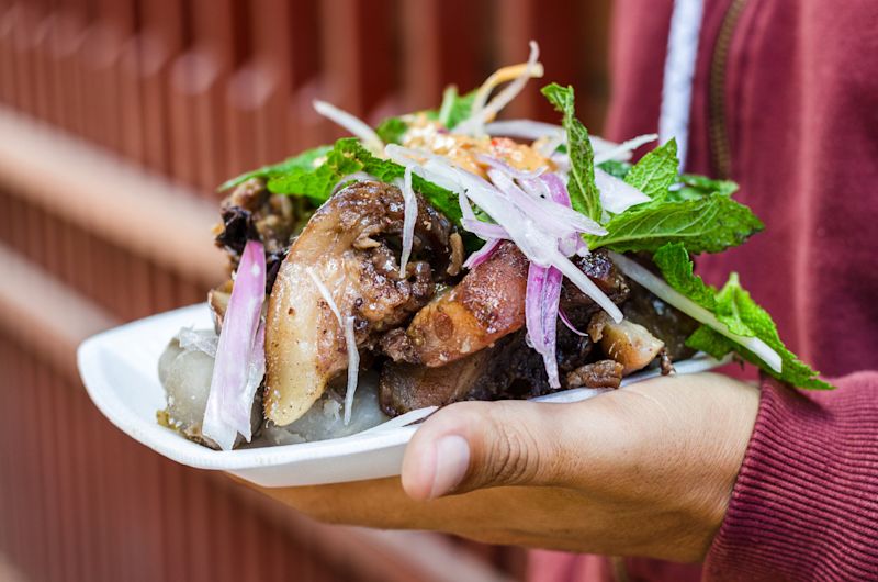 Close up of Crispy fried Pork dish served with salad and sauce at Peruvian restaurant or street food in Cusco